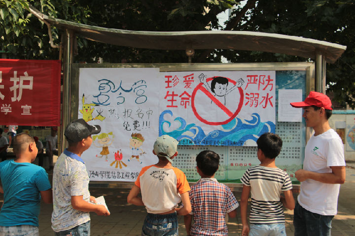 志愿者给学生讲解防溺水宣传海报(摄影 任双辉).JPG